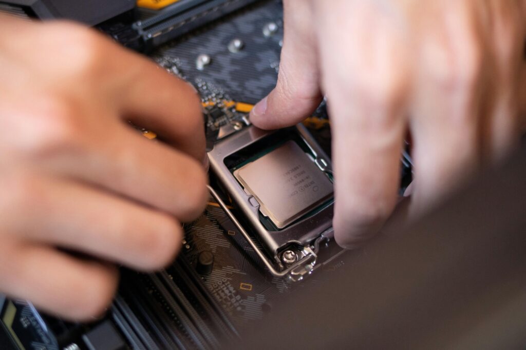 Home Detailed view of hands installing a CPU onto a motherboard inside a computer setup.